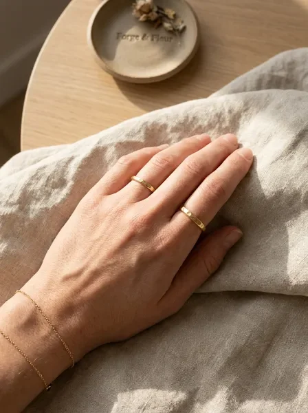 Hand wearing simple artisan stacking rings on linen
